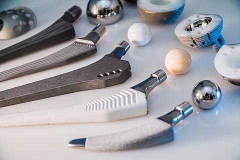 Auf einem Tisch liegen Hüftprothesen aus verschiedenen Materialien. 