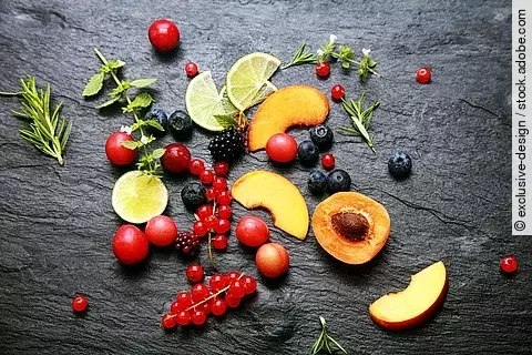Früchte, Beeren, Kräuter auf einem Granitteller