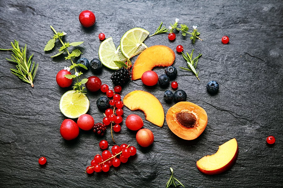 Früchte, Beeren, Kräuter auf einem Granitteller