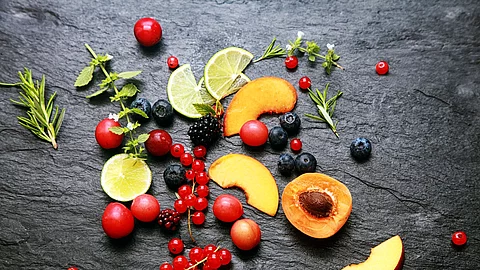 Früchte, Beeren, Kräuter auf einem Granitteller