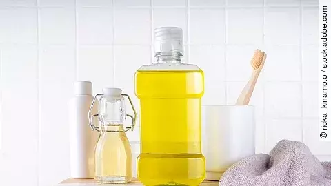 Oil Pulling Mouthwash, dental oral hygiene rinse aid liquid, trendy alternative detoxifying mouthwash with toothbrush, toothpaste for cleaning teeth on bath background Materialien zur Mundpflege, Öl in Mundwasserflasche