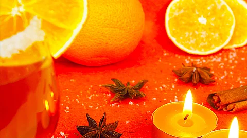 Gals mit Weihnachtspunsch mit Orangen und Teelichtern 