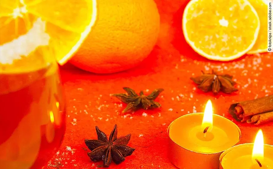 Gals mit Weihnachtspunsch mit Orangen und Teelichtern 