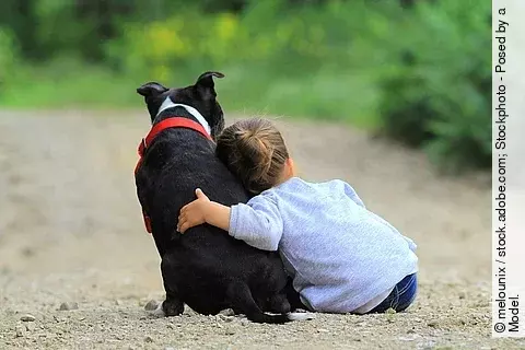 Kleines Mädchen sitzt neben Hund