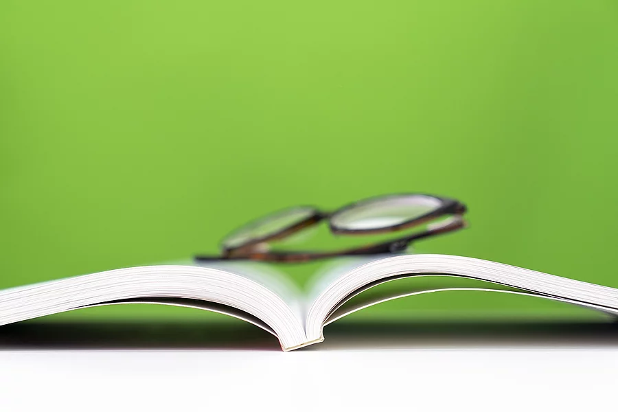 ein aufgeschlagenes Buch, darauf liegt eine Brille