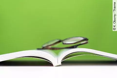 ein aufgeschlagenes Buch, darauf liegt eine Brille