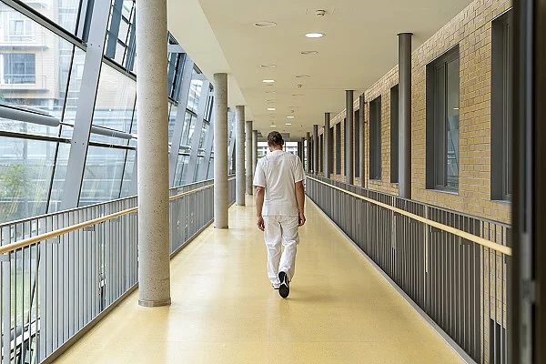 Mann in Dienstkleidung, der einen Krankenhausflur entlangläuft.
