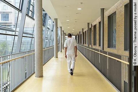Mann in Dienstkleidung, der einen Krankenhausflur entlangläuft.