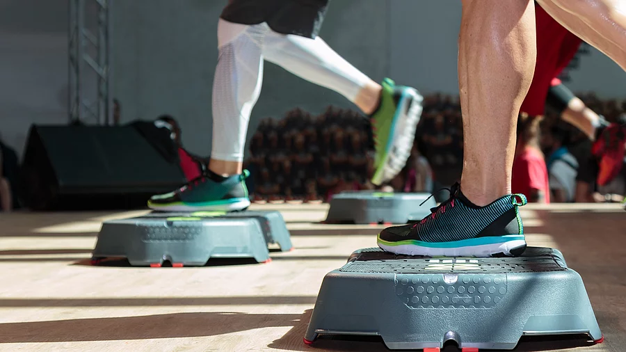 Fitness-Workout auf dem Stepper 2 Paar Männerbeine auf dem Stepper