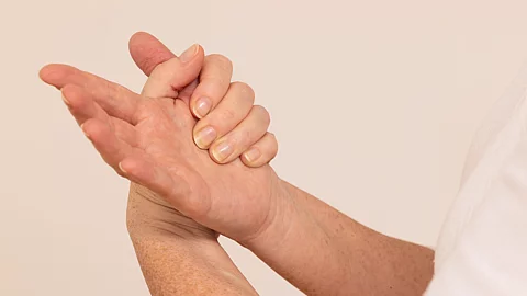 Frau umfasst mit der linken Hand den rechten Daumen