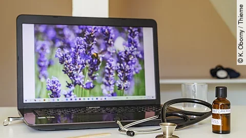 Symbolbild Integrativmedizin: Laptop mit Lavendel auf dem Screen, Stethoskop und Braunfläschchen