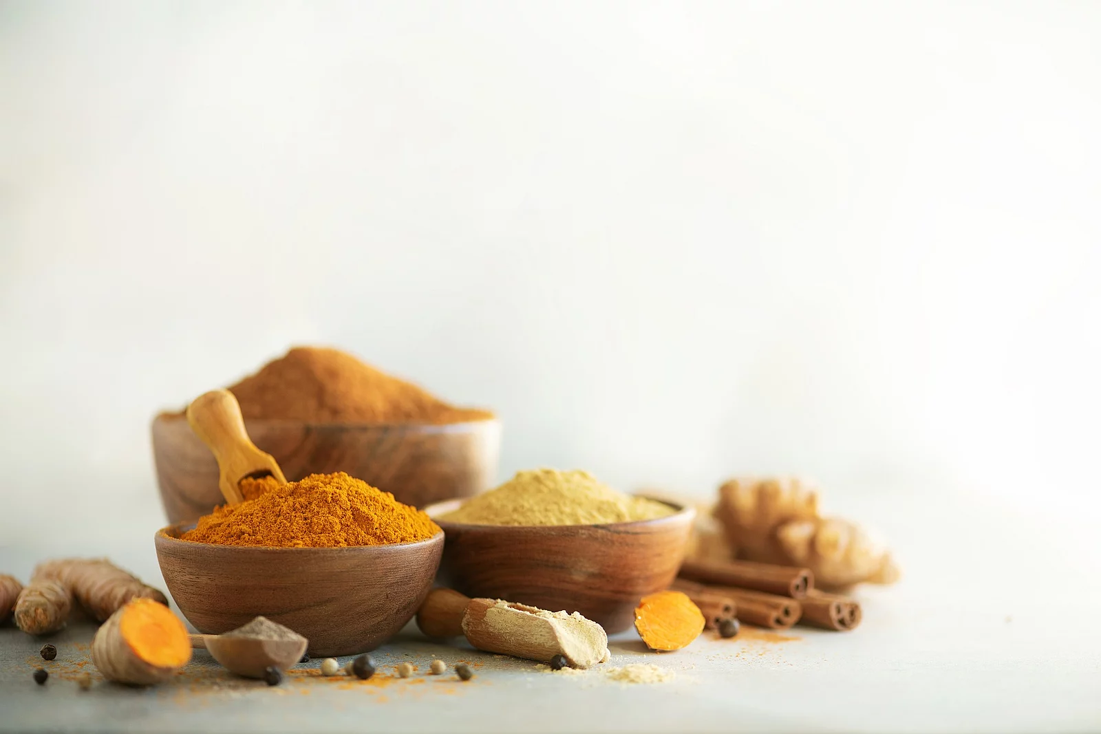 Ingredients for hot ayurvedic drink. Turmeric powder, curcuma root, cinnamon, ginger, lemon over grey background. Copy space, square crop. Spices for alternative medicine