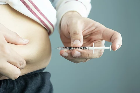 Mann mit Adipositas spritzt sich in den Bauch