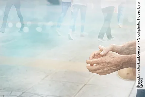 allein sitzende Person in einer Straßensituation, es sind nur die Hände zu sehen