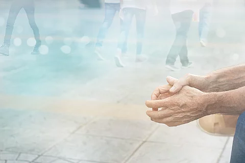 allein sitzende Person in einer Straßensituation, es sind nur die Hände zu sehen