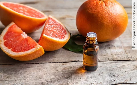 Fläschchen mit ätherischem Öl vor einem Hintergrund von Zitrusfrüchten/Orangen/Grapefruits. 
