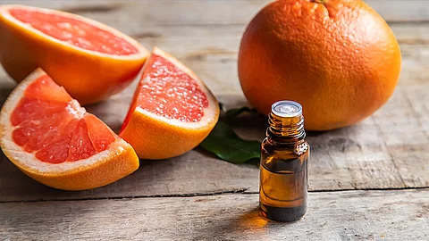 Fläschchen mit ätherischem Öl vor einem Hintergrund von Zitrusfrüchten/Orangen/Grapefruits. 