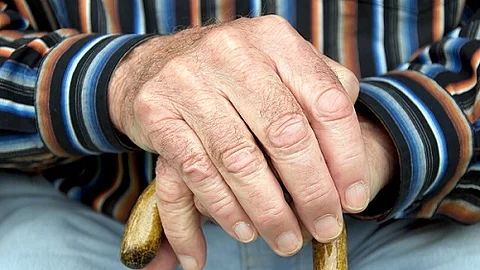 Senior stützt Hände auf Gehstock
