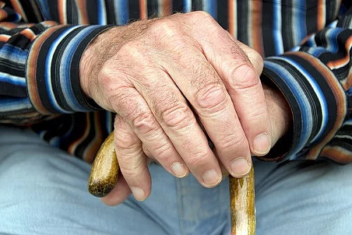 senior and cane Senior stützt Hände auf Gehstock
