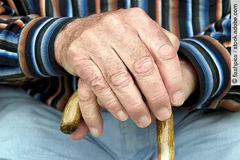 Senior stützt Hände auf Gehstock