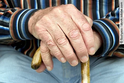 Senior stützt Hände auf Gehstock