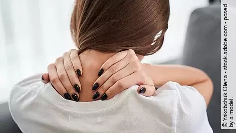 Junge Frau greift sich an die Halswirbelsäule