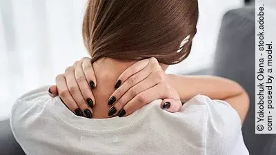 Junge Frau greift sich an die Halswirbelsäule