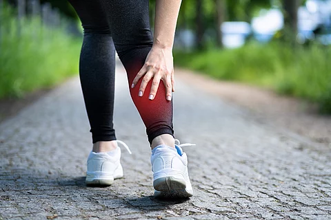 Frau beim Joggen, hat Wadenschmerz