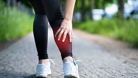 Frau beim Joggen, hat Wadenschmerz