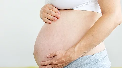 Frau hält ihren Schwangerschaftsbauch.