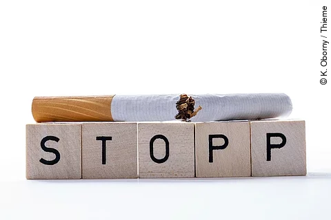 Zerbrochene Zigrarette liegt auf Spielwürfeln mit dem Wort STOPP