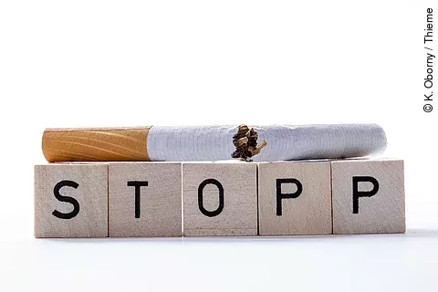 Zerbrochene Zigrarette liegt auf Spielwürfeln mit dem Wort STOPP