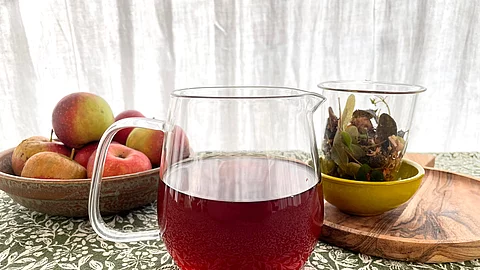 Gläserne Teekanne mit dunklem Kräutertee auf Steintisch