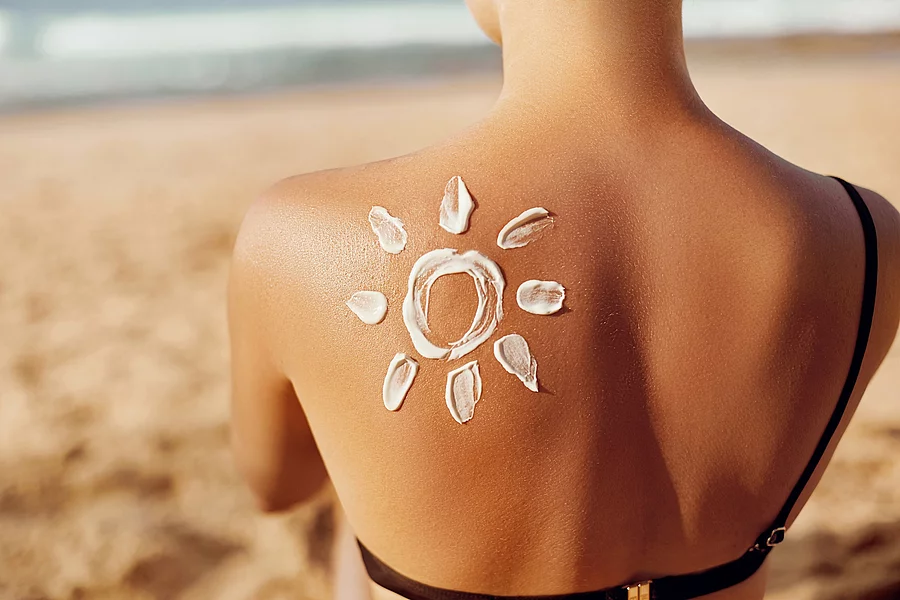 Frau am Strand mit Sonnencreme in Form einer Sonne auf dem Rücken