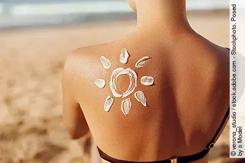 Frau am Strand mit Sonnencreme in Form einer Sonne auf dem Rücken