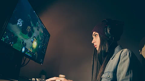 junge Frau mit Kopfhörern spielt am Computer