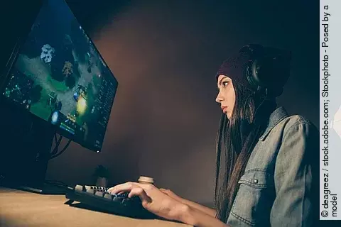 junge Frau mit Kopfhörern spielt am Computer