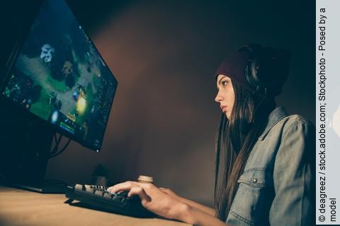 junge Frau mit Kopfhörern spielt am Computer