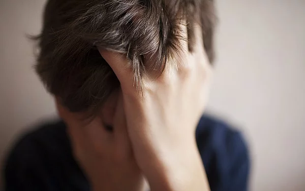 Teen boy covers his face with his hands Junge mit Händen vor dem Gesicht