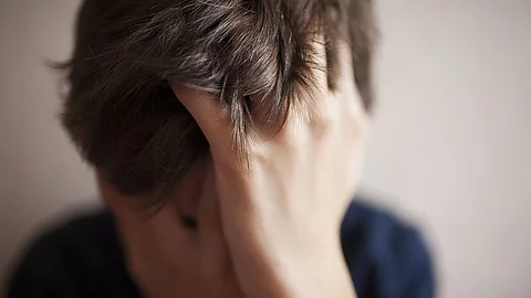 Junge mit Händen vor dem Gesicht