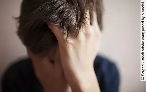 Junge mit Händen vor dem Gesicht