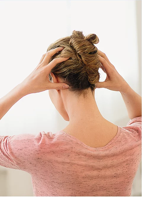 Frau von hinten, Hände am Kopf zur Muskelentspannung