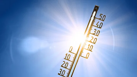Thermometer vor blauem Himmel und Sonne