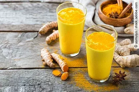 2 Gläser Kurkumamilch auf Holzuntergrund