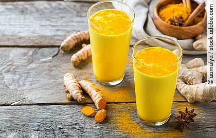 2 Gläser Kurkumamilch auf Holzuntergrund