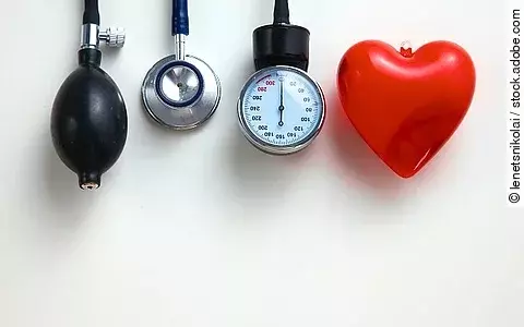 Blutdruckmanschette, rotes Plastikherz und Stethoskop.