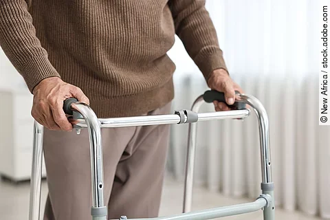 Nahaufnahme eines älteren Herren, der eine Gehhilfe nutzt.