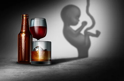 Illustration: Fötus neben Bierflasche und Rotweinglas vor grauem Hintergrund