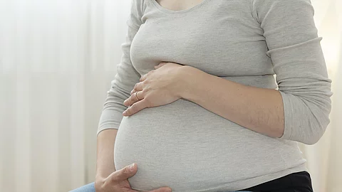Schwangere Frau hält ihren Bauch.