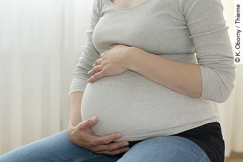 Schwangere Frau hält ihren Bauch.